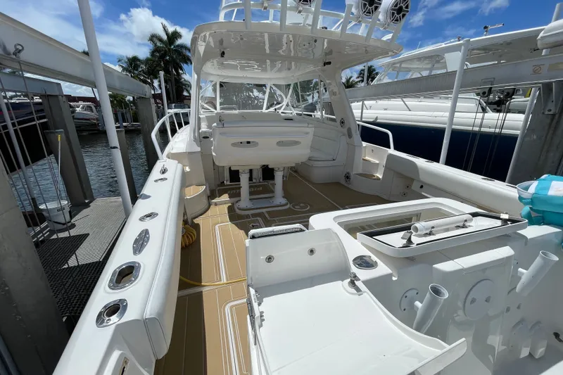 Slide: The Image of 2010 Intrepid 390 Sport Yacht docked, showcasing spacious deck and seating area under clear skies. - 18