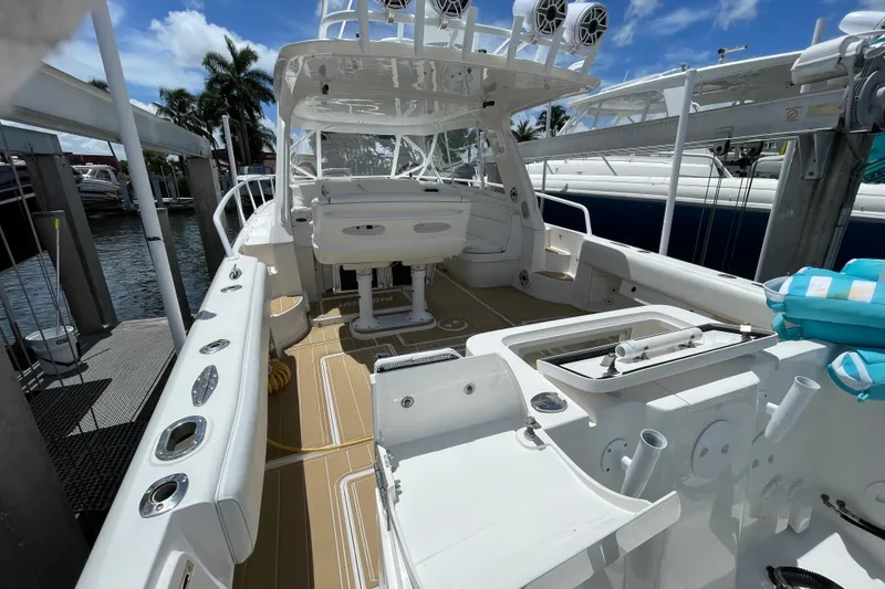 Slide: The Image of 2010 Intrepid 390 Sport Yacht docked, showcasing spacious deck and seating area under clear skies. - 17
