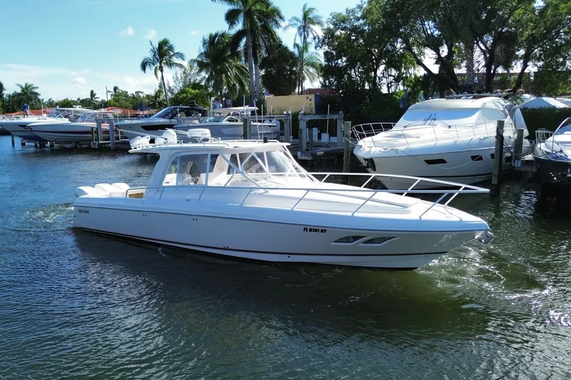 The Image of 2010 Intrepid 390 Sport Yacht cruising in a marina with palm trees in the background. - 0