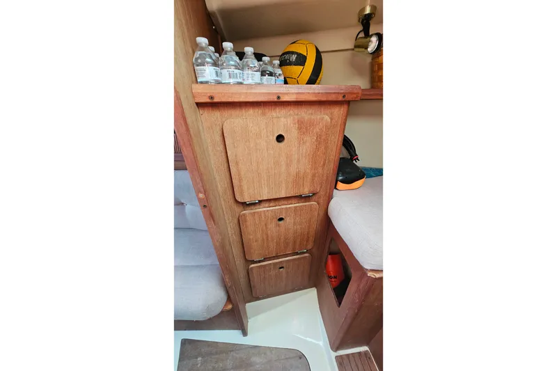 Slide: The Image of Interior of 1989 Hunter 30 sailboat with wooden storage cabinets and bottled water. - 17