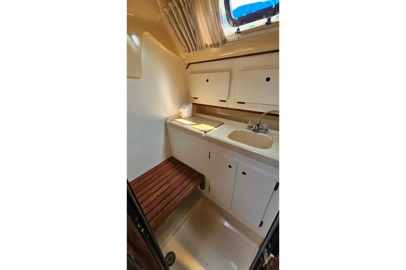 Slide: The Image of Interior of 1989 Hunter 30 sailboat galley with sink, cabinets, and wooden bench. - 21