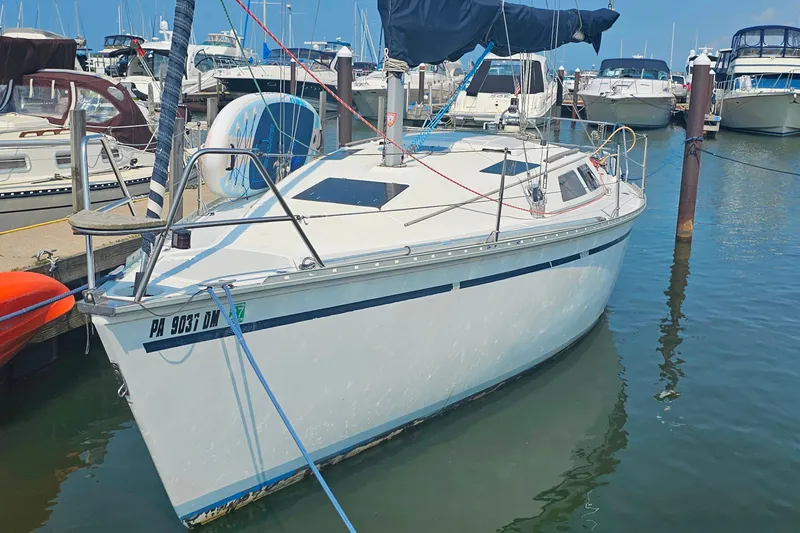 The Image of 1989 Hunter 30 sailboat docked in marina, surrounded by other boats under clear blue sky. - 1