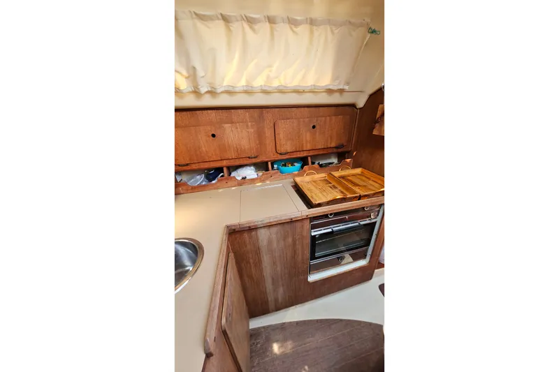 Slide: The Image of 1989 Hunter 30 sailboat interior kitchen with wooden cabinets and stove. - 20