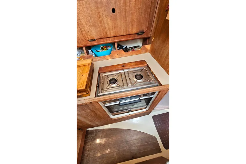 Slide: The Image of Compact kitchen area in a 1989 Hunter 30 sailboat, featuring a stove and storage. - 24