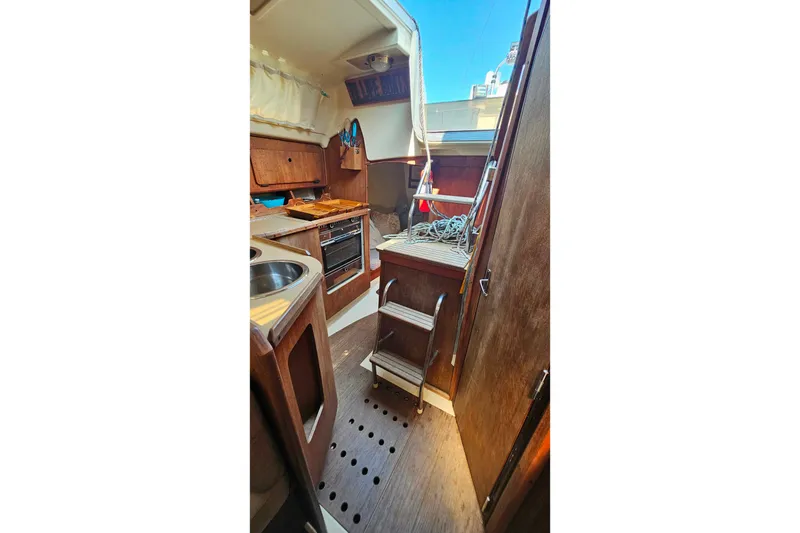Slide: The Image of Interior of a 1989 Hunter 30 sailboat featuring a compact kitchen and wooden cabinetry. - 23