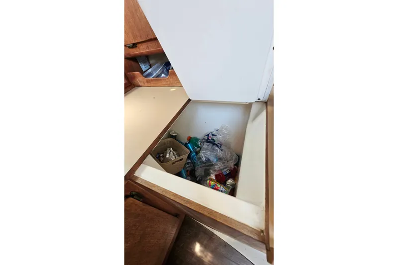 Slide: The Image of Storage compartment in 1989 Hunter 30 boat with assorted items and containers. - 25