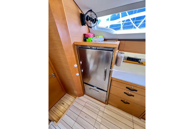 Slide: The Image of Interior of 2018 Jeanneau 54 yacht featuring a compact kitchen with stainless steel fridge. - 43