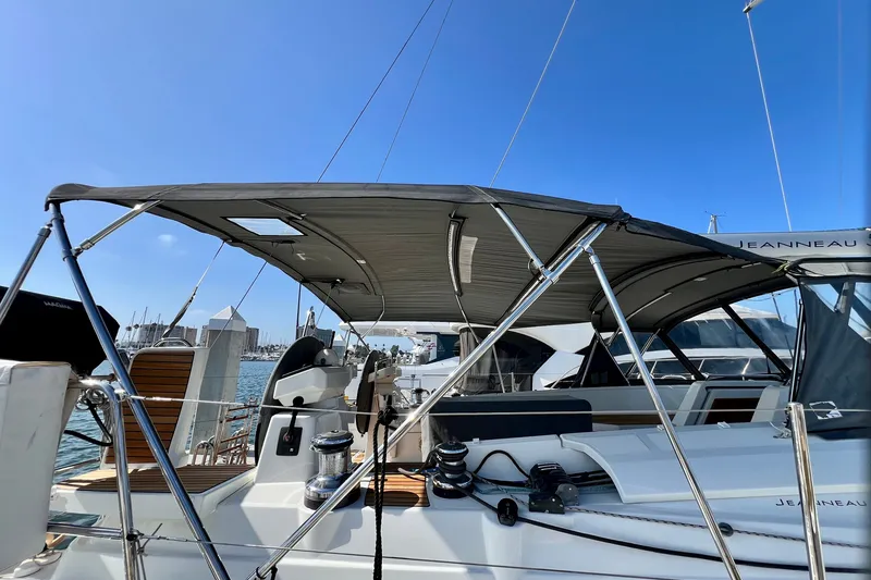 Slide: The Image of 2018 Jeanneau 54 sailboat with canopy, docked at marina under clear blue sky. - 14