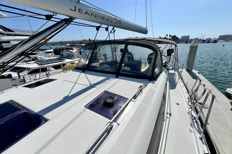 Slide: The Image of 2018 Jeanneau 54 sailboat docked at marina, showcasing sleek design and spacious deck. - 24