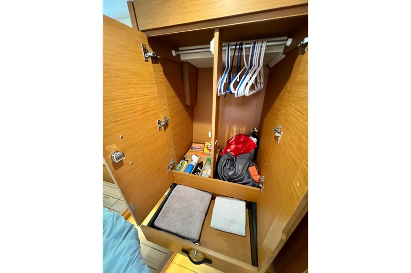 Slide: The Image of Wooden closet interior on a 2018 Jeanneau 54 yacht, featuring hangers and storage items. - 95