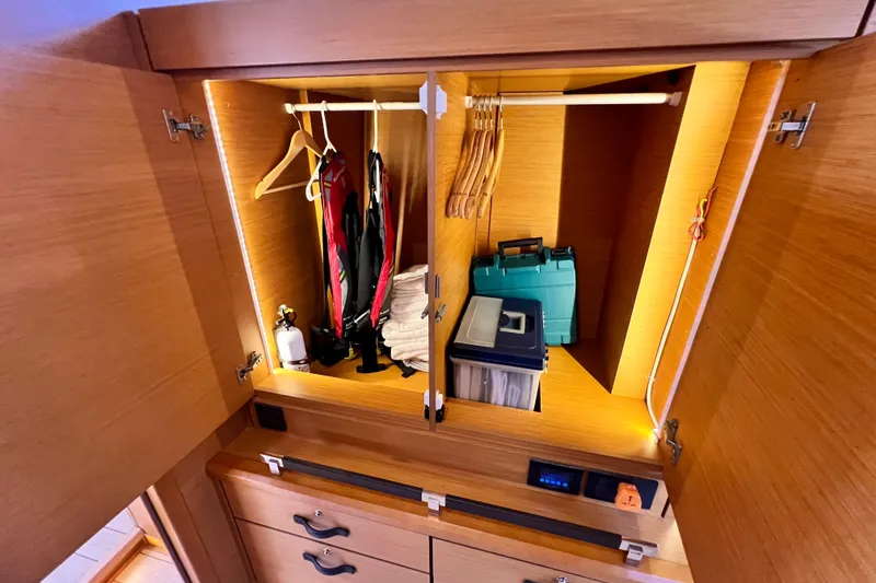 Slide: The Image of Wooden closet interior on a 2018 Jeanneau 54 yacht, featuring hangers and storage boxes. - 77