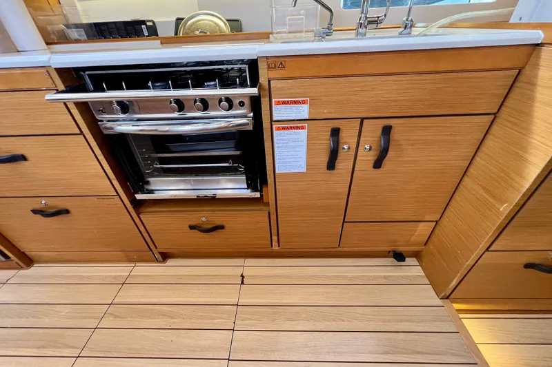 Slide: The Image of Galley kitchen in 2018 Jeanneau 54 yacht with stove and wooden cabinetry. - 45