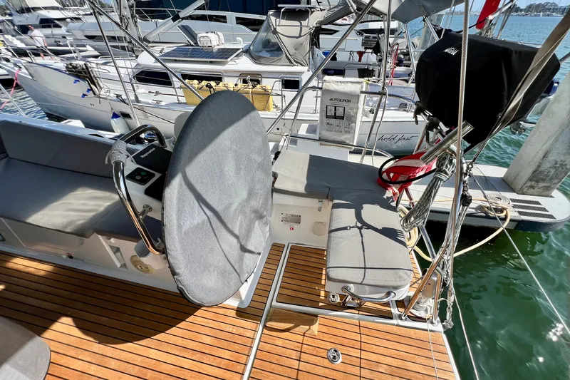 Slide: The Image of 2018 Jeanneau 54 sailboat cockpit with covered steering wheel and teak flooring at marina. - 31