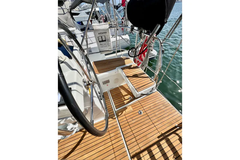 Slide: The Image of 2018 Jeanneau 54 yacht deck with teak flooring and steering wheel, docked on calm water. - 37