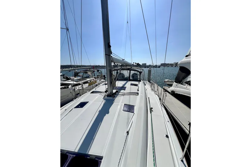 Slide: The Image of 2018 Jeanneau 54 sailboat docked in a sunny marina, showcasing sleek deck design. - 22