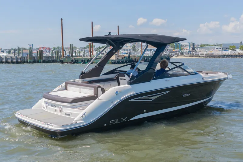 Slide: The Image of A 2016 Sea Ray SLX 250 cruising on calm water. It features a sleek design and a black canopy. - 1