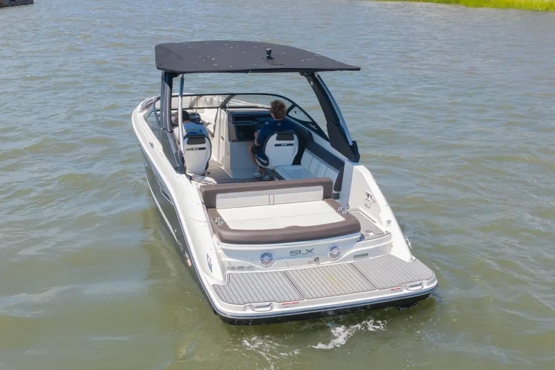 Slide: The Image of A 2016 Sea Ray SLX 250 cruising on calm waters. It features a black canopy. - 2