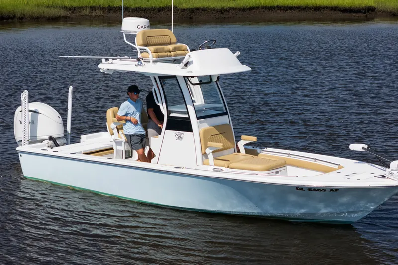 The Image of 2024 Sportsman Masters 247OE Bay Boat cruising on calm water with two passengers. - 1