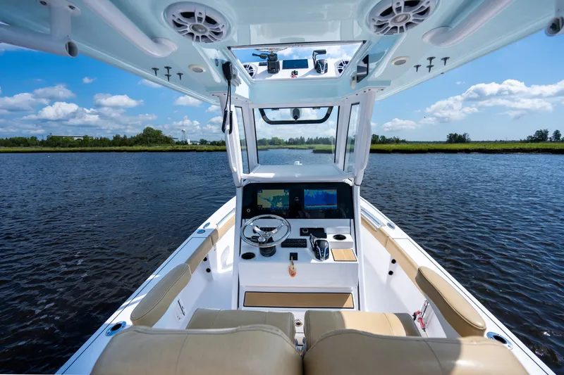 Slide: The Image of 2024 Sportsman Masters 247OE Bay Boat interior with dual screens on a calm waterway. - 9