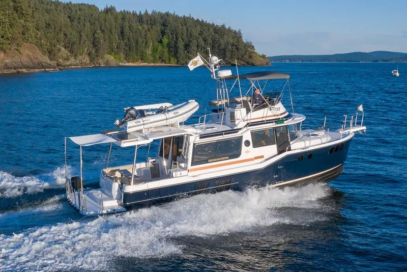 Slide: The Image of Manufacturer Provided Image: 2025 Ranger Tugs R-43 CB cruising on blue water near forested shoreline. - 1
