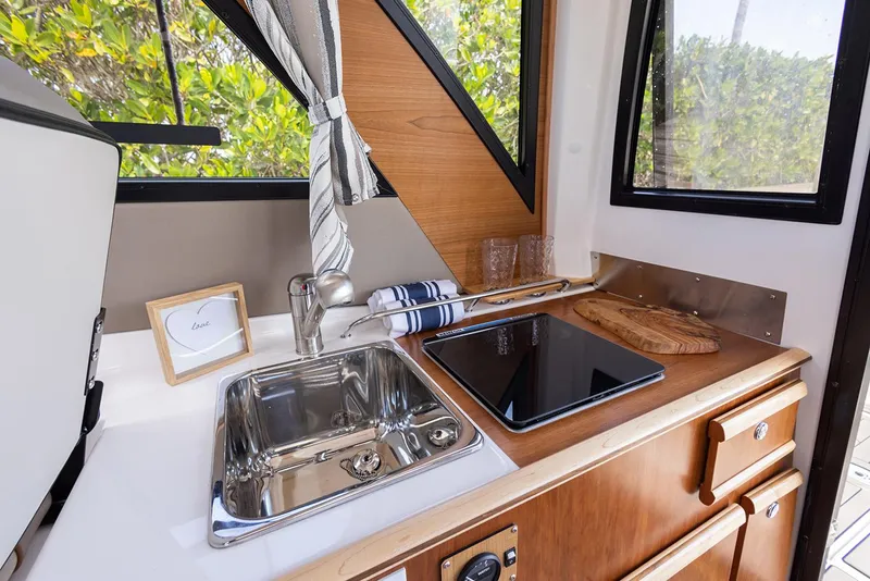 Slide: The Image of Manufacturer Provided Image: 2025 Cutwater C-248 Coupe kitchenette with sink, stove, and window view. - 11
