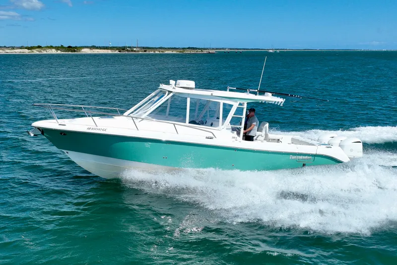 Slide: The Image of A 2016 Everglades 350LX boat speeds across blue water, with a coastline in the background. - 15