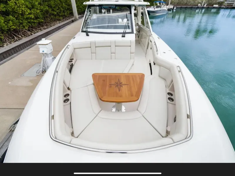 Slide: The Image of The image shows the bow of a 2022 Boston Whaler 380 Realm with a wooden table. - 41
