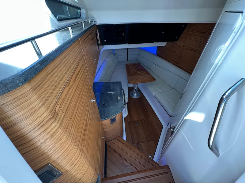 Slide: The Image of Interior of 2022 Boston Whaler 380 Realm, featuring wood finishes and a cozy seating area. - 29