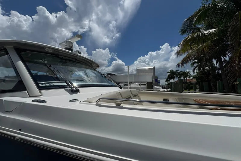 Slide: The Image of 2022 Boston Whaler 380 Realm boat under a bright blue sky with palm trees. - 48