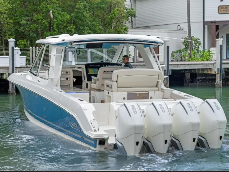 Slide: The Image of 2022 Boston Whaler 380 Realm boat with four engines, docked near a marina. - 1