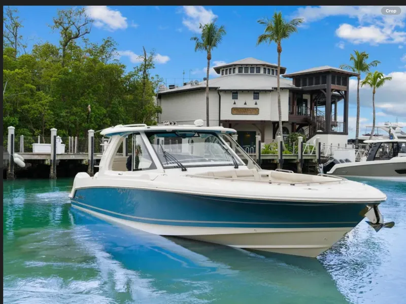 Slide: The Image of 2022 Boston Whaler 380 Realm boat docked near waterfront building, surrounded by palm trees. - 3