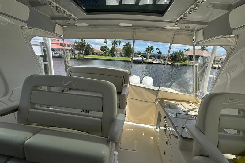 Slide: The Image of Interior view of 2022 Boston Whaler 380 Realm boat with seating and waterway backdrop. - 15