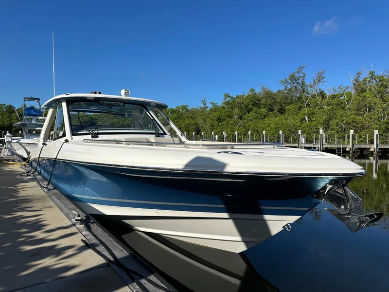 Slide: The Image of 2022 Boston Whaler 380 Realm docked, reflecting on calm water under clear blue sky. - 5