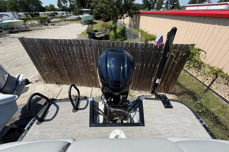 Slide: The Image of 2023 Bennington 23 LX boat with outboard motor, parked near wooden fence. - 16