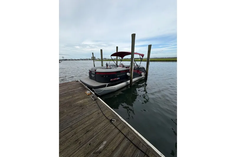 The Image of 2023 Bennington 23 LX pontoon boat docked on calm water. - 1