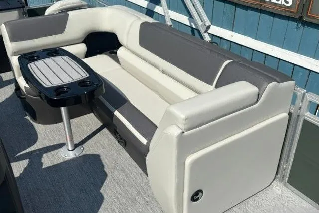 Slide: The Image of 2026 Sun Tracker Fishin' Barge 22 DLX interior with gray seating and table. - 14