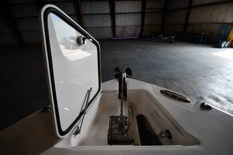 Slide: The Image of Open anchor compartment of 2015 Edgewater 320CC boat in a dimly lit warehouse. - 26