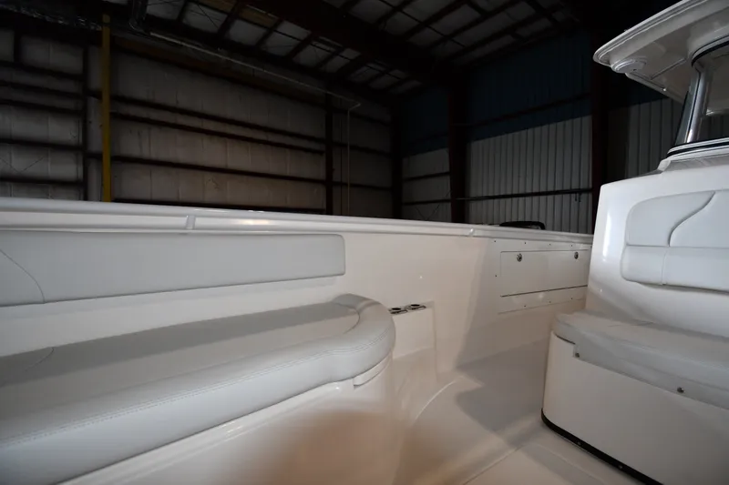 Slide: The Image of 2015 Edgewater 320CC boat interior with white seating in a warehouse setting. - 24
