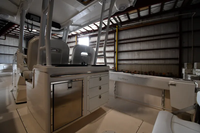 Slide: The Image of 2015 Edgewater 320CC boat interior in a warehouse, featuring seating and storage compartments. - 13