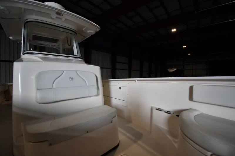 Slide: The Image of 2015 Edgewater 320CC boat interior with seating, under dim warehouse lighting. - 23