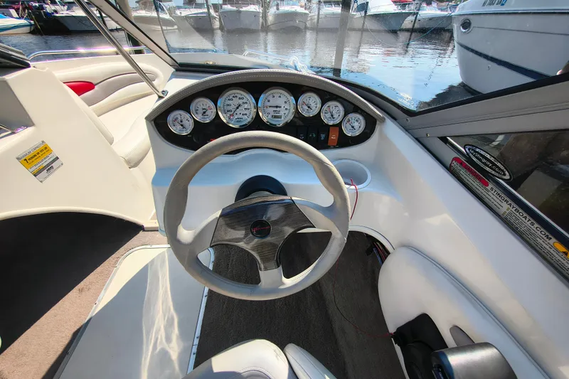 Slide: The Image of 2004 Stingray 185 LS/LX boat dashboard with steering wheel and gauges, docked at marina. - 6