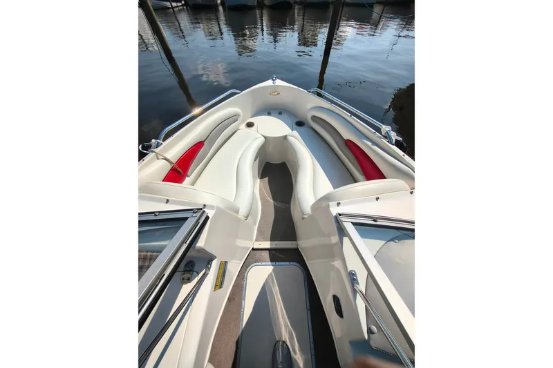 Slide: The Image of 2004 Stingray 185 LS/LX boat interior with white seating and red accents, docked by the water. - 9