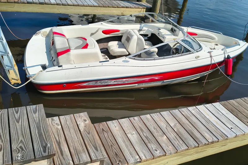 The Image of 2004 Stingray 185 LS/LX boat docked, featuring red and white design with comfortable seating. - 1