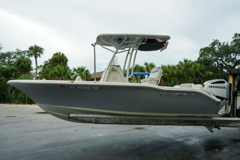 Slide: The Image of 2022 Key West 219 FS boat with Honda engine on trailer, surrounded by palm trees. - 43