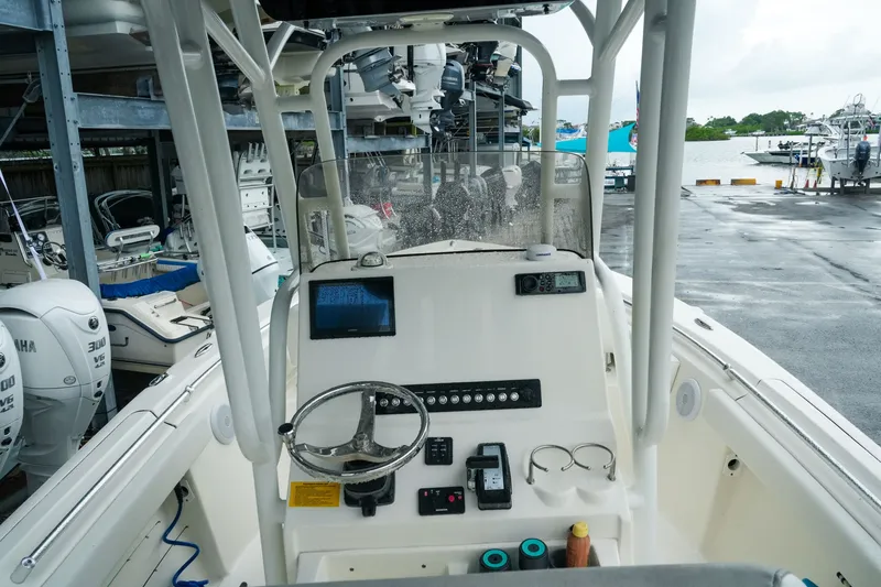 Slide: The Image of 2022 Key West 219 FS boat dashboard with steering wheel and controls in marina setting. - 13