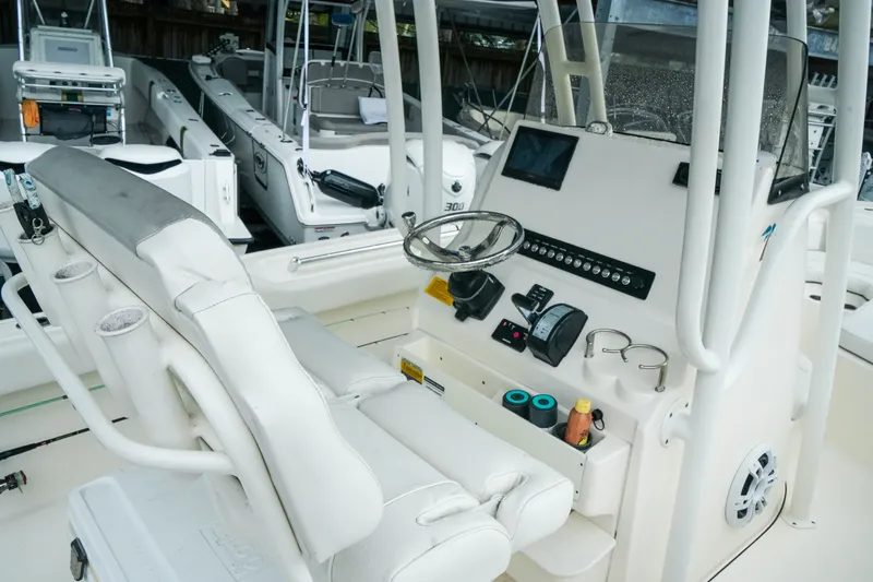 Slide: The Image of 2022 Key West 219 FS boat console with steering wheel and controls in marina setting. - 25