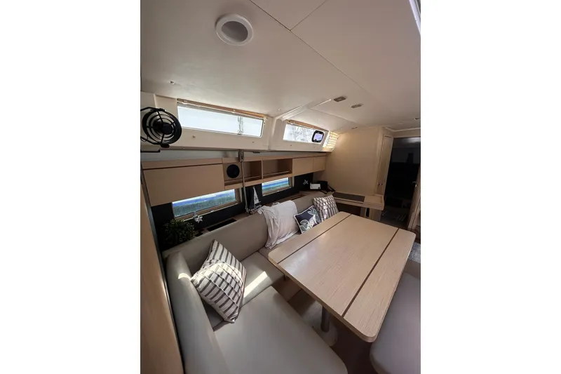 Slide: The Image of Interior of 2020 Beneteau Oceanis 461 yacht, featuring a cozy dining area with cushions. - 19
