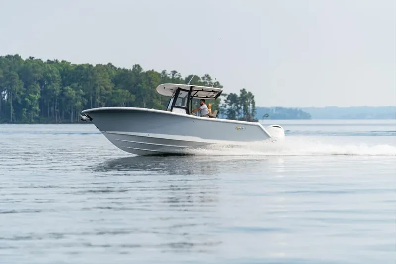 The Image of 2027 Sea Hunt Gamefish 25 cruising on a serene lake with forested shoreline. - 1