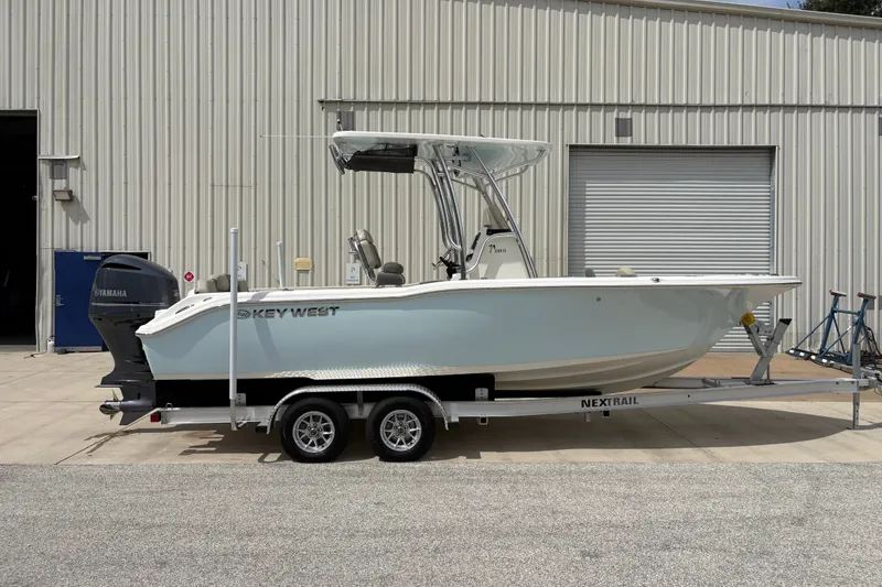 Slide: The Image of 2025 Key West 239 FS boat on trailer, parked outside a warehouse. - 1