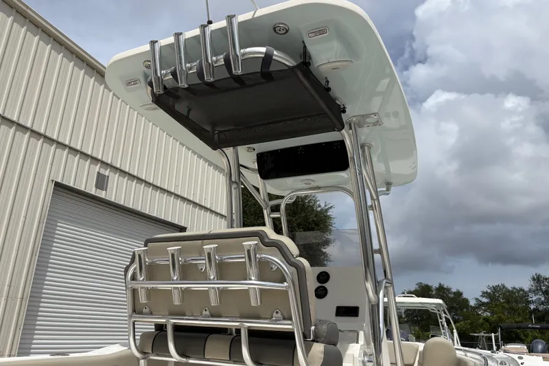 Slide: The Image of 2025 Key West 239 FS boat with T-top and rod holders, parked near a warehouse. - 9